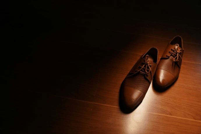 a pair of brown shoes sitting on top of a wooden floor